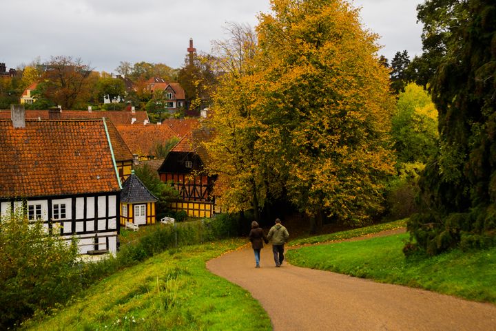 To%20personer%20g%E5r%20p%E5%20en%20sti%20i%20en%20efter%E5rslandskab%20med%20farverige%20tr%E6er%20og%20traditionelle%20huse%20i%20baggrunden.
